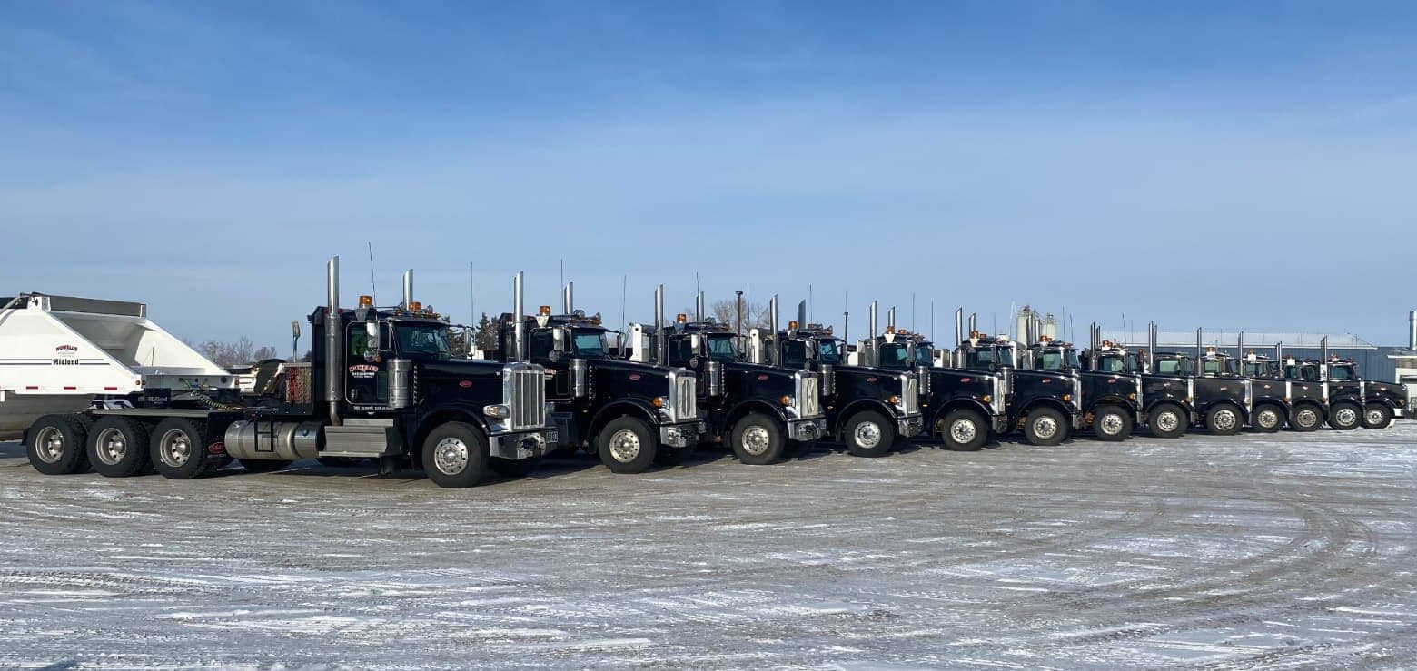 Fleet of black trucks with trailers