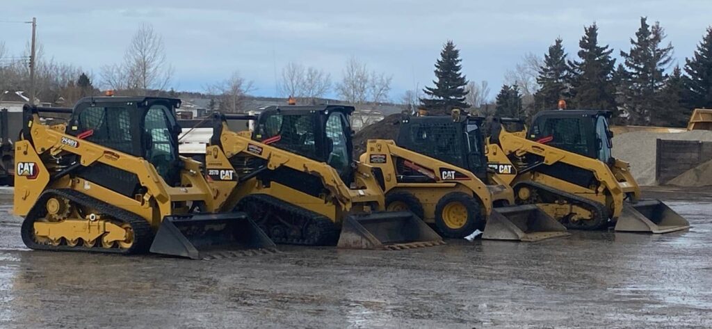 Four skidsteers lined up in yard