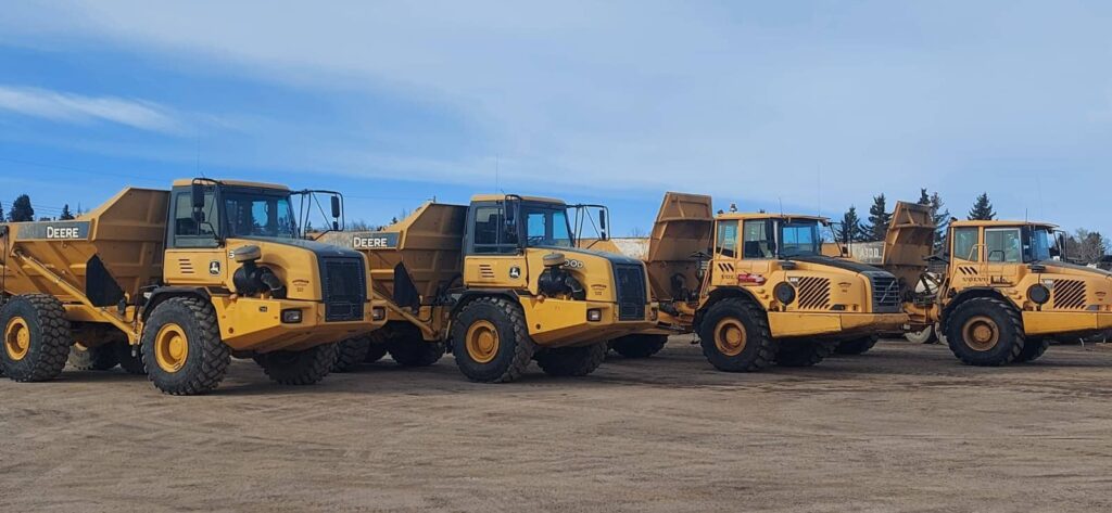 Rock truck heavy equipment lined up in yard