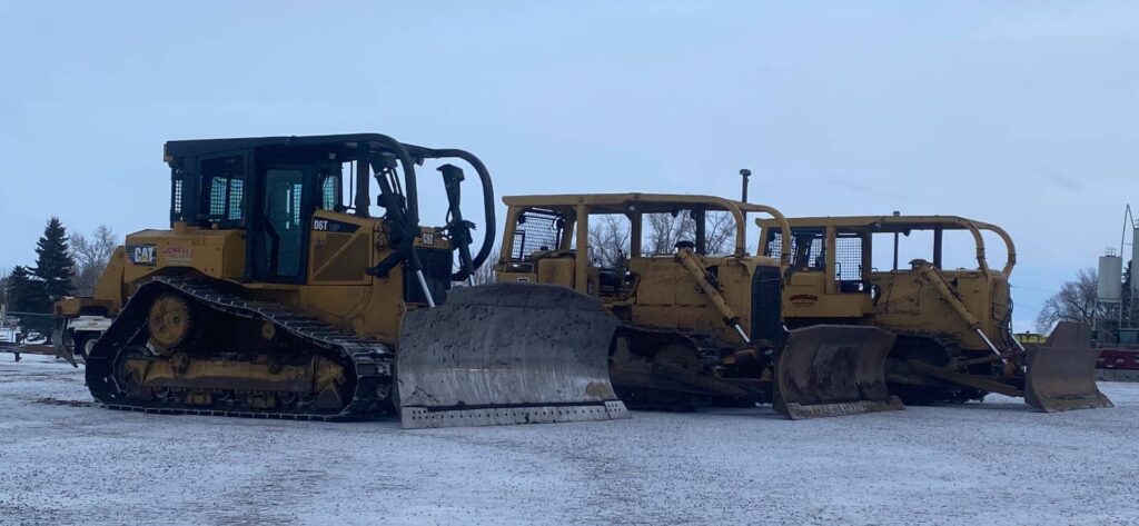 Three construction dozers lined up in yard